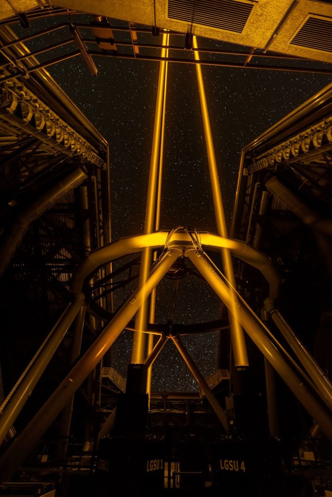 A telescope silhouetted against a starry night sky